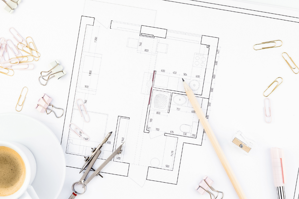 floor plan with coffee, compass and pencil on it