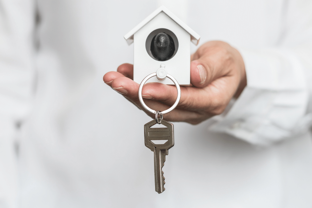 someone holding a small house with a key attached