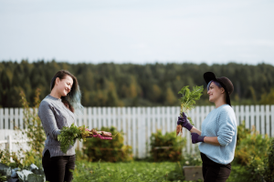 two women talking in a garden holding vegetables