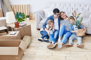 family sat on the floor in new home next to cardboard boxes