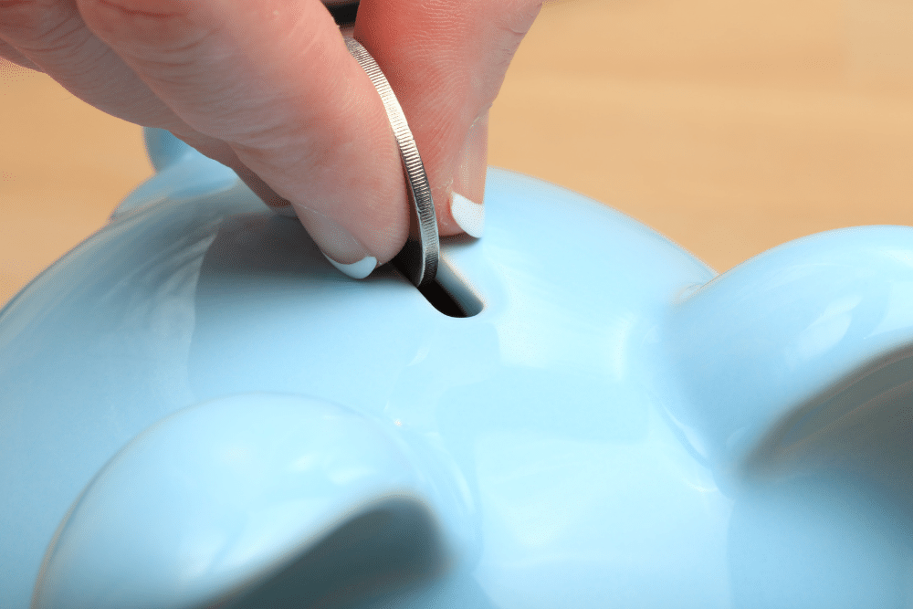 coin being put into a light blue piggy bank