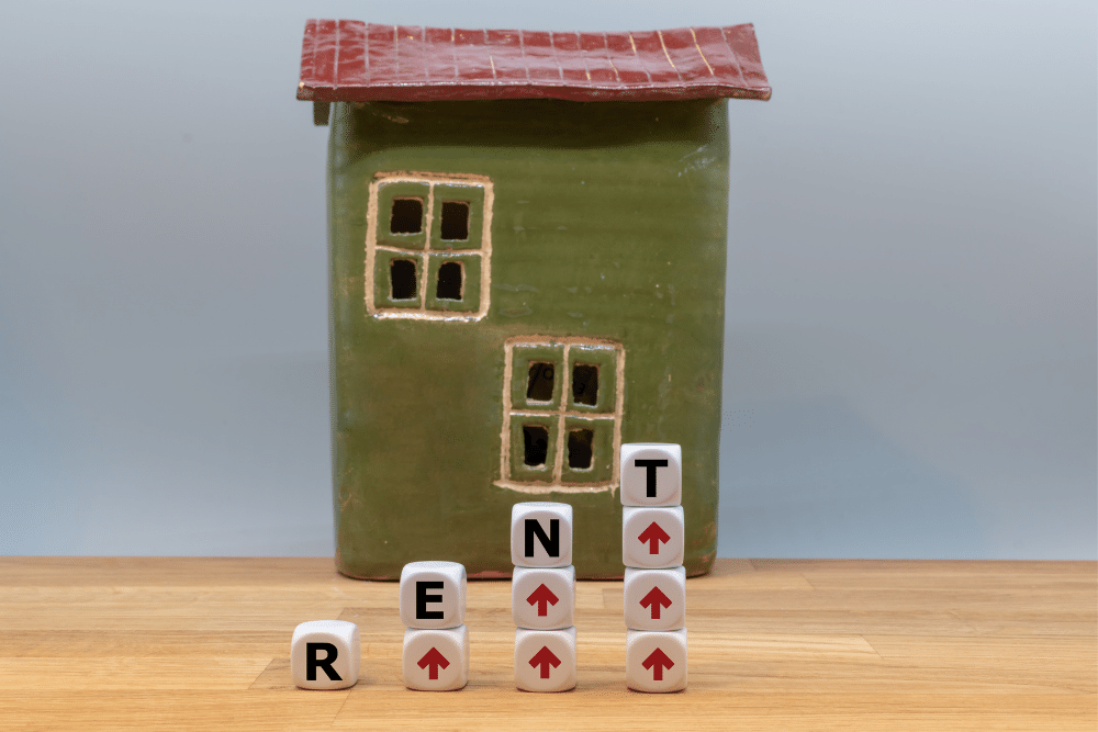 a home with the word rent written in the foreground alongside red upward arrows