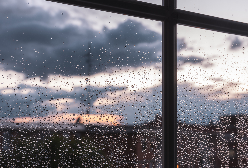 Window frame perspective with raindrops at sunset