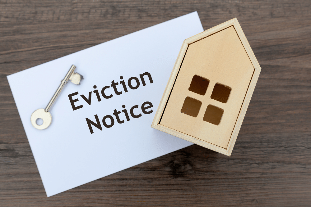 A key, small wooden house and piece of paper saying 'eviction notice'