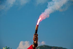 red flare in hand against a blue sky