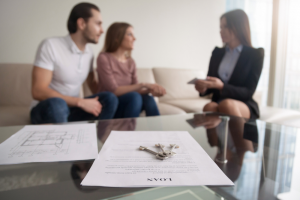 keys on a piece of paper, couple discussing with mortgage adviser in background
