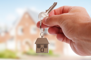 hand holding house keys with house keychain against blurred background