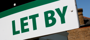 a green sign that says 'let by' in front of a house