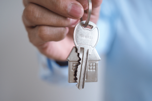 close up of hands holding a key with a house keychain