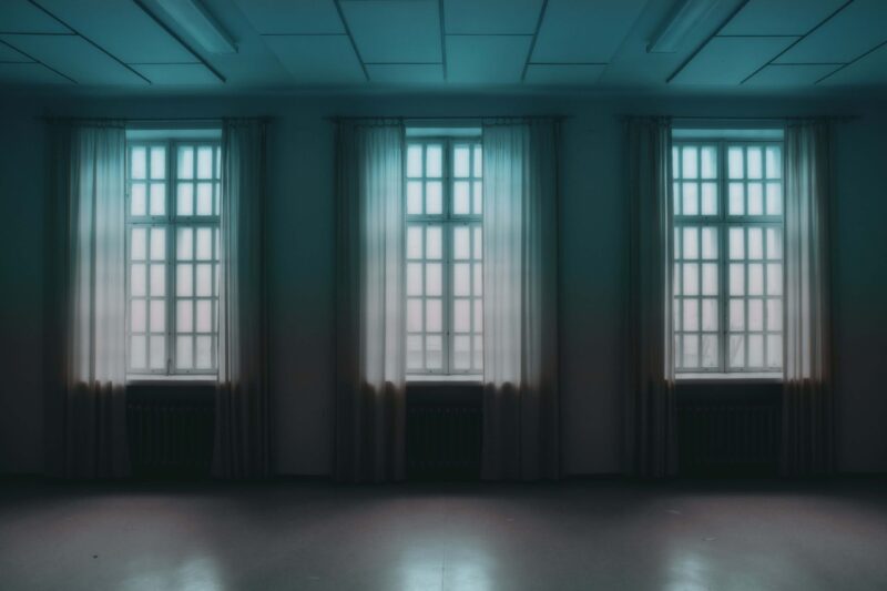 Windows in a row, dark room, white curtains